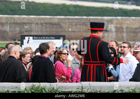 A Tower of London Beefeater speaks to a group of sightseeing tourists before entering the Tower London England UK EU Stock Photo