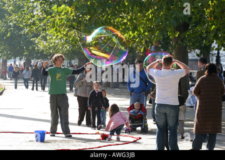 A street performer blows giant bubbles to entertain tourists and children near the London Eye on the Thames London England UK EU Stock Photo
