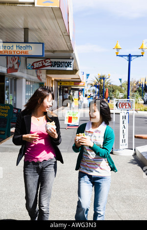 Two young women walking with hamburgers in hands Stock Photo