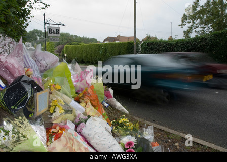 Car moving past floral tributes to fatal accident victim August 2006 A2100 Battle East Sussex England Britain UK Stock Photo