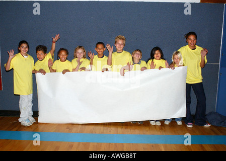 Mixed race group of boys and girls hold up blank white banner Stock Photo