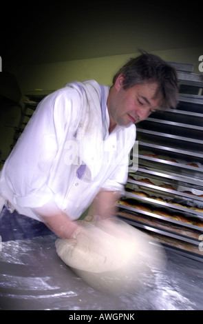 A bakers hand's blur as he kneads dough UK Stock Photo