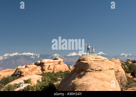 Two hikers standing on top of a rock formation in Arches National Park Stock Photo