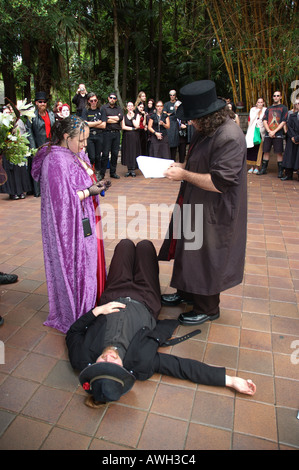 Exchanging rings at Goth  wedding ceremony over the fallen body of a discordian Pope Stock Photo