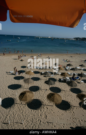 Thatched umbrellas make pools of shade on the beach named Praia da Rainha in the city of Cascais Portugal Stock Photo