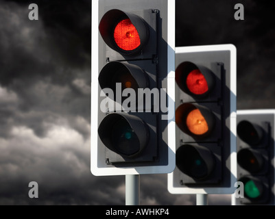 ROW OF THREE ROAD TRAFFIC LIGHTS SHOWING RED AMBER GREEN SEQUENCE WITH STORMY SKY Stock Photo