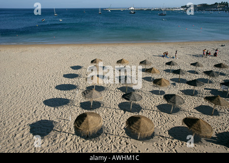 Thatched umbrellas make pools of shade on the beach named Praia da Rainha in the city of Cascais Portugal Stock Photo