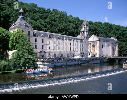 French Benedictine Abbey at Brantôme Dordogne in Nouvelle-Aquitaine region bell tower beside river Dronne with tour boat and weir Périgueux France EU Stock Photo