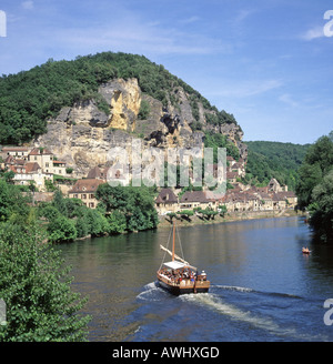 La Roque Gageac beside the river Dordogne with tourists on sightseeing tour boat and picturesque village nestling below cliffs Stock Photo