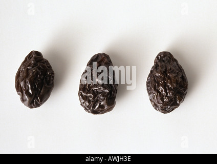 Three prunes against white background, close-up Stock Photo