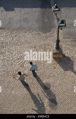 Two men walking on a cobbled plaza as seen from above Stock Photo