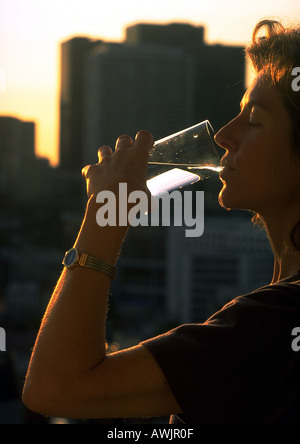 Woman drinking water, high rises in background Stock Photo