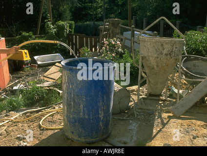 Person using hose to put water into plastic barrel Stock Photo