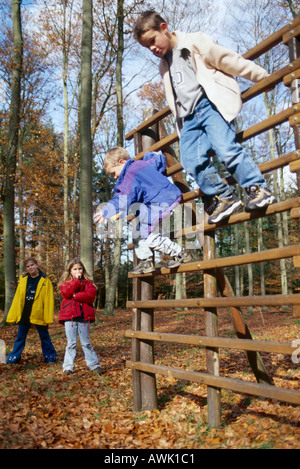 two boys playing on monkey bars with two girls standing in background Stock Photo