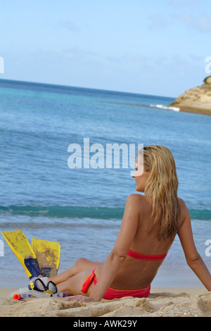woman wearing pink bikini and yellow fins sat on the beach Stock Photo