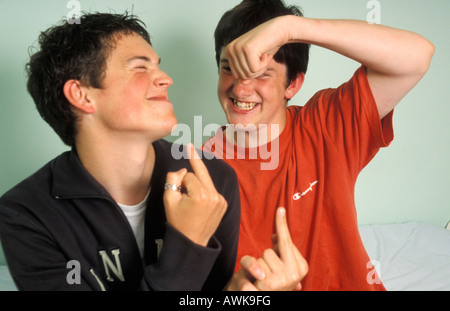 two teenage boys making silly hand gestures to each other messing about Stock Photo
