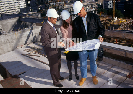 Couple and architect discussing blueprints at construction site Stock Photo