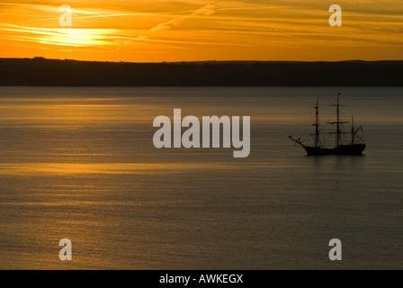 A square Rigged Sailing Ship in St Austell Bay, with the Sun Rising over the Land Stock Photo