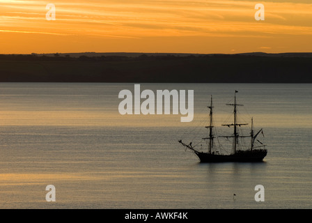 A square Rigged Sailing Ship in St Austell Bay, with the Sun Rising over the Land Stock Photo