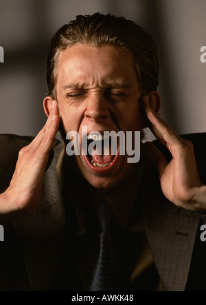 Man covering ears and screaming Stock Photo