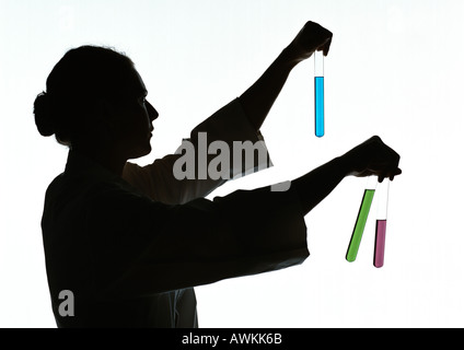 Woman holding test tubes containing different colored liquids, silhouette. Stock Photo