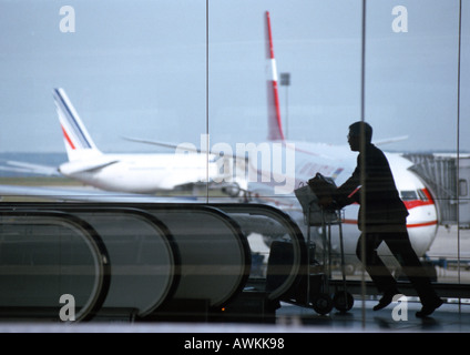 Man hurrying with luggage cart in airport Stock Photo