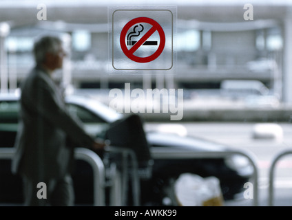 Man standing outside, no smoking sign on window in foreground Stock Photo