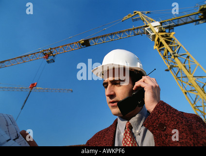 Man wearing hard hat, using cell phone, low angle view Stock Photo