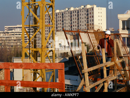 Man wearing hard hat, using cell phone in construction site Stock Photo