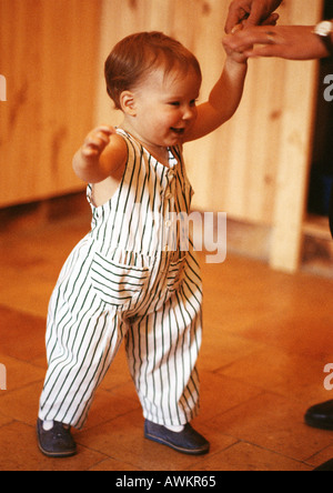 Toddler walking, holding adult hand Stock Photo