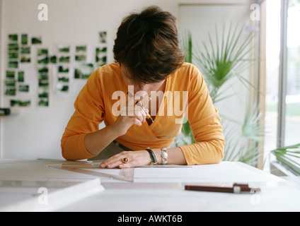 Woman bending over table, holding set square and pen Stock Photo