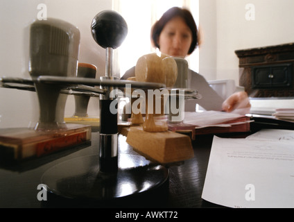 Stampers on rack, and woman sitting at desk, blurred Stock Photo