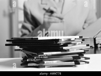 Pile of floppy disks on table, person in background, b&w Stock Photo