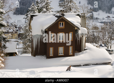 Chalet standing in deep snow with huge frozen icicles hanging from roof at Engelberg in Obwalden Canton in central Switzerland Stock Photo