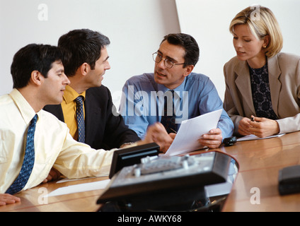 Three businessmen and a businesswoman examining document Stock Photo
