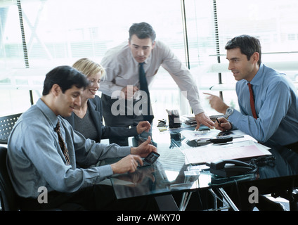 Business associates working together at desk, one using calculator Stock Photo
