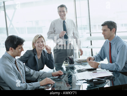 Business associates around desk, one looking at calculator Stock Photo