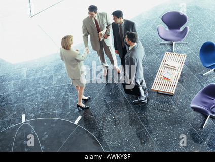 Business associates shaking hands in lobby, overhead view Stock Photo