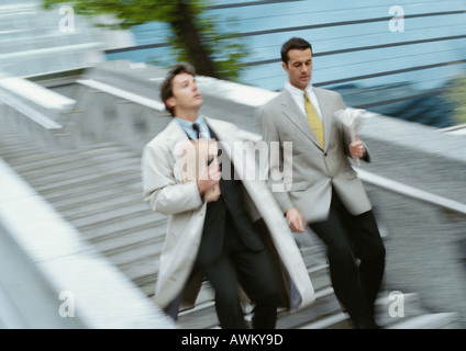 Two businessmen going down stairs side by side, blurred Stock Photo