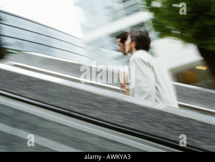 Two businessmen walking up stairs outside, blurred Stock Photo