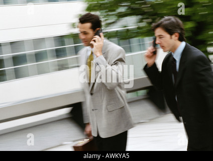 Two businessmen using cell phones outside, blurred Stock Photo