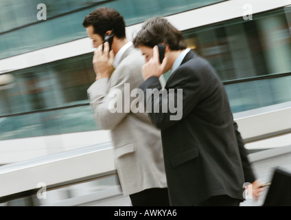 Two businessmen using cell phones outside, side view Stock Photo