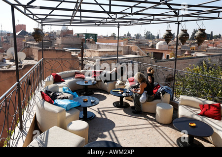 Young female tourists relaxing on the rooftop patio of Café Arabe, enjoying the view over the historic Medina quarter, Marrakes Stock Photo