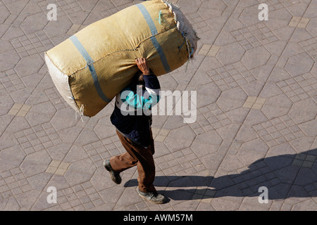 Man carrying a big parcel on his shoulders, Djemaa el Fna, Marrakech, Morocco, Africa Stock Photo