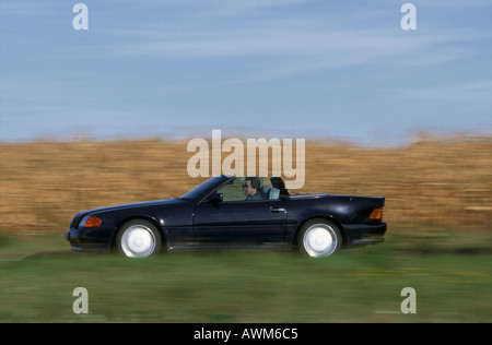 Side profile of man driving convertible car on road Stock Photo