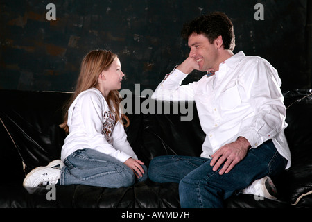 Father and daughter sitting on the couch and talking Stock Photo