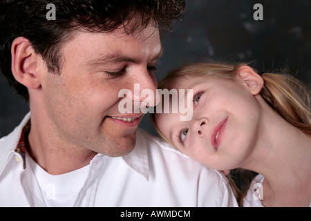 Daughter affectionately resting her head on her father's shoulder Stock Photo