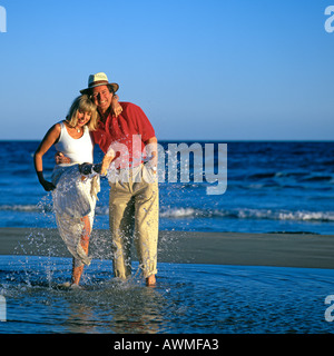 MATURE COUPLE SPLASHING IN SEA Stock Photo
