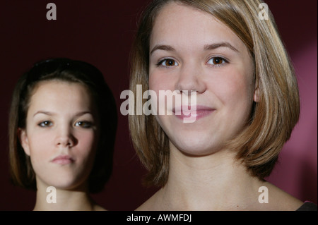 Two girls, pre-teen, early teens, one smiling the other looking serious Stock Photo