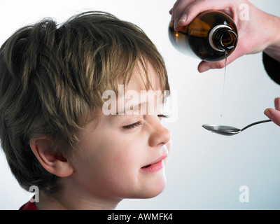 child refusing to take medicine from spoon Stock Photo